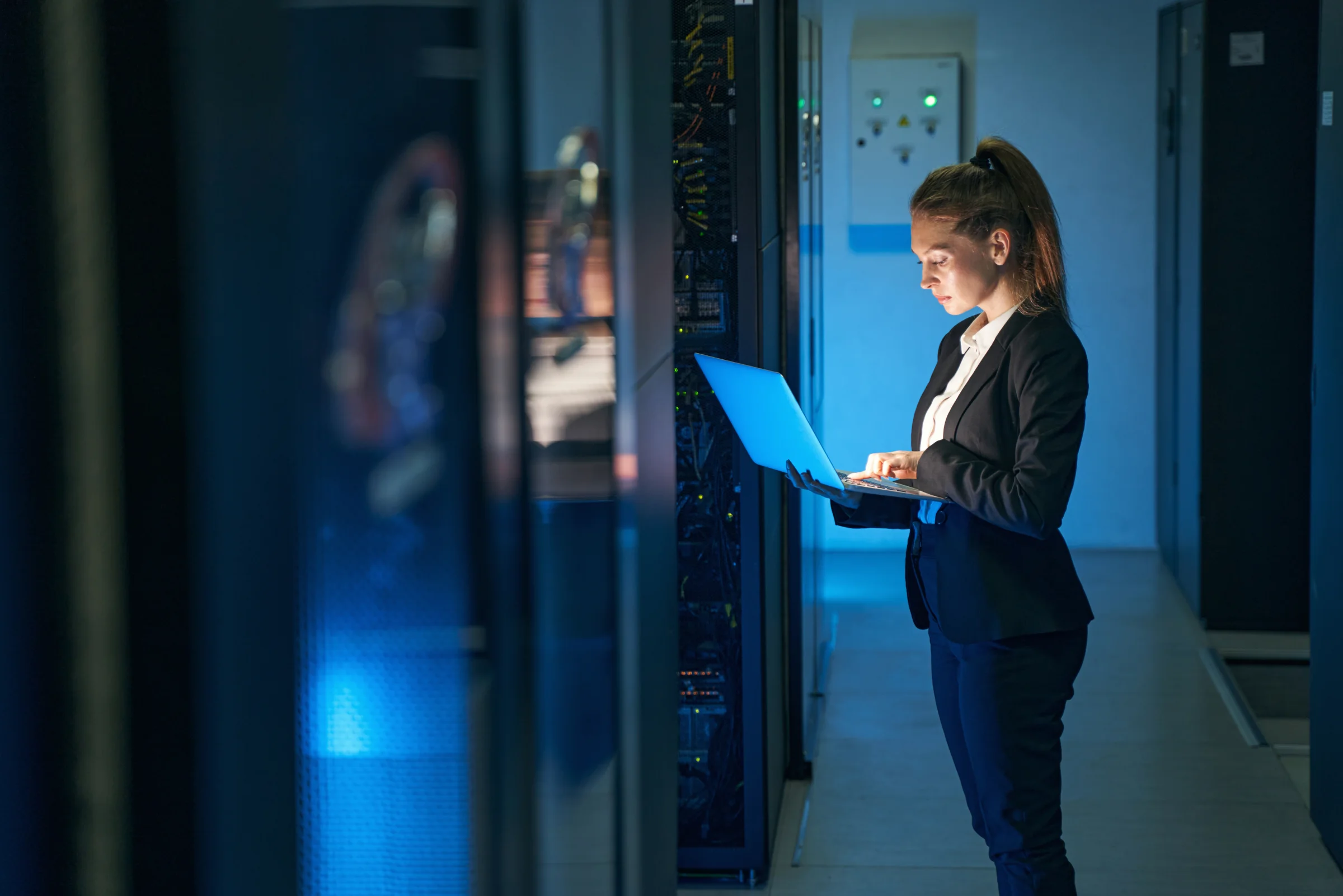 Engineer working beside server racks with a laptop