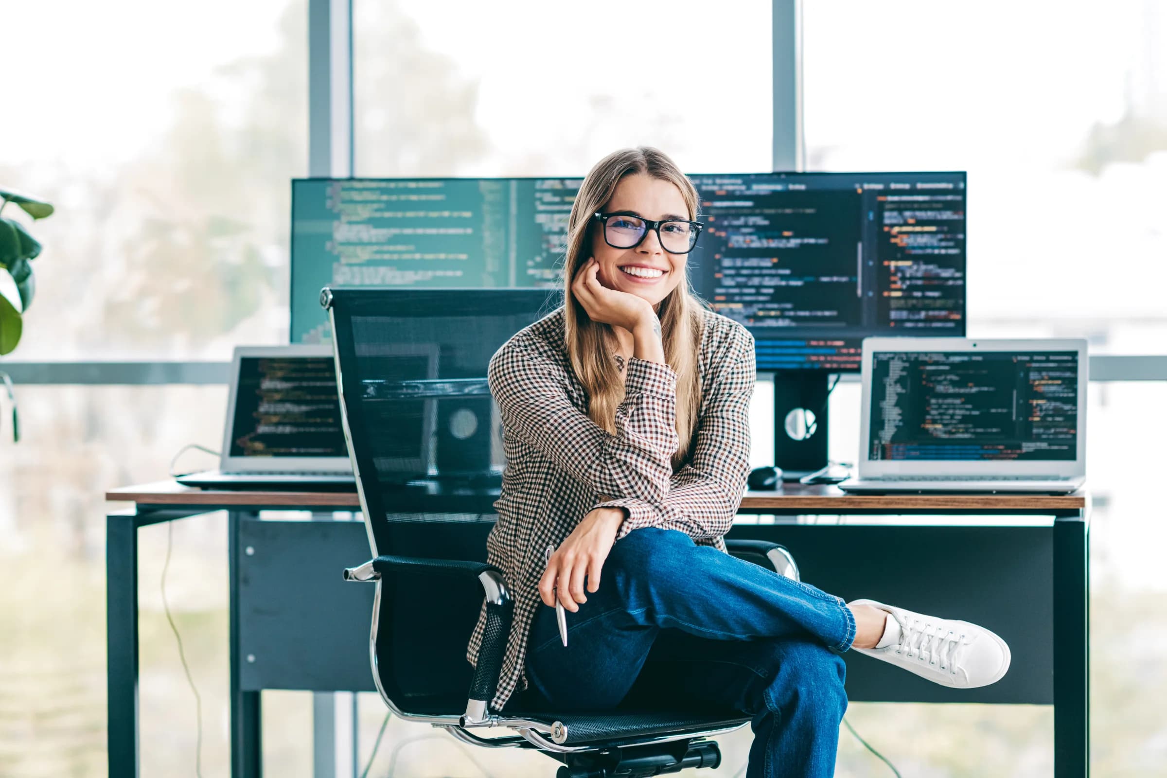 Software engineer seated in front of multiple screens showing code
